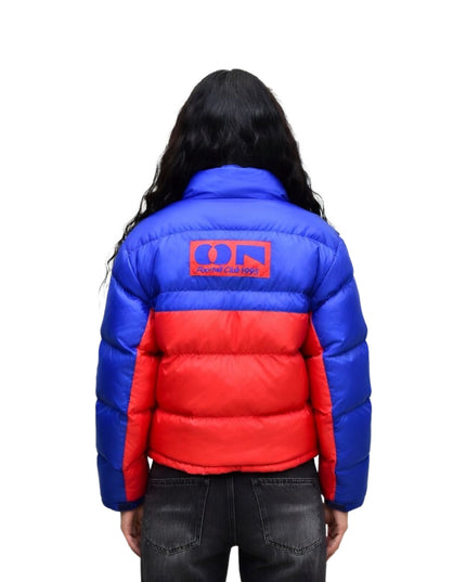 Person wearing a blue and red puffer jacket with a logo on the back against a white background