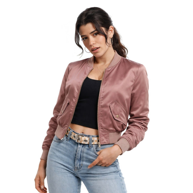 Woman wearing a pink satin jacket, black top, and light blue jeans on a white background