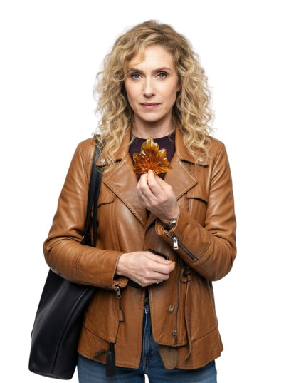 Woman in a brown leather jacket holding an autumn leaf against a white background
