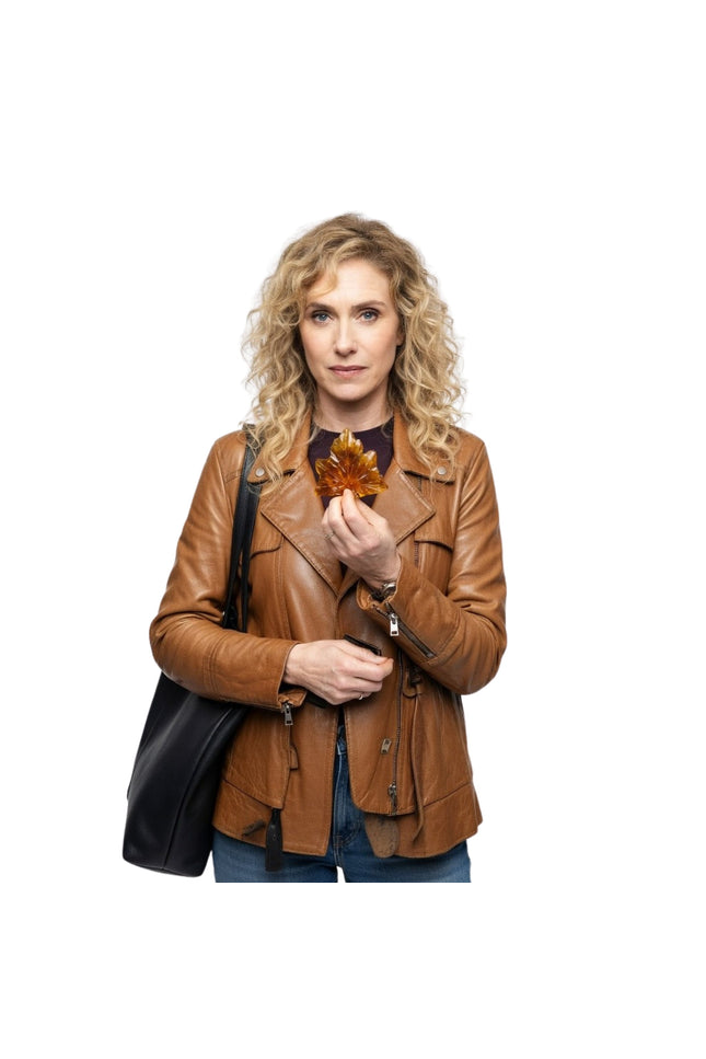 Woman in a brown leather jacket holding an autumn leaf against a white background