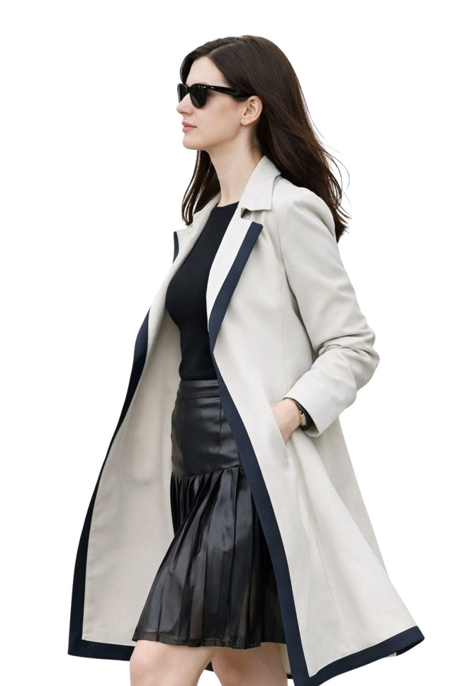 Woman wearing a long beige coat with black trim on a white background
