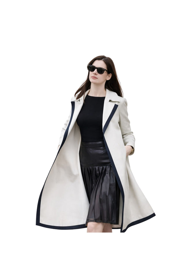 Woman wearing a long white coat with black trim on a white background