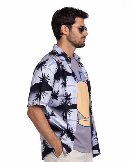 Man wearing a patterned shirt with palm tree design on a white background