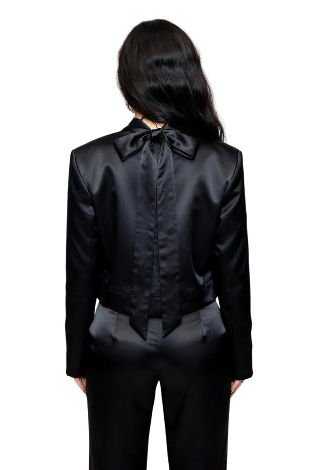 Person wearing a black satin outfit with a bow tie on a white background