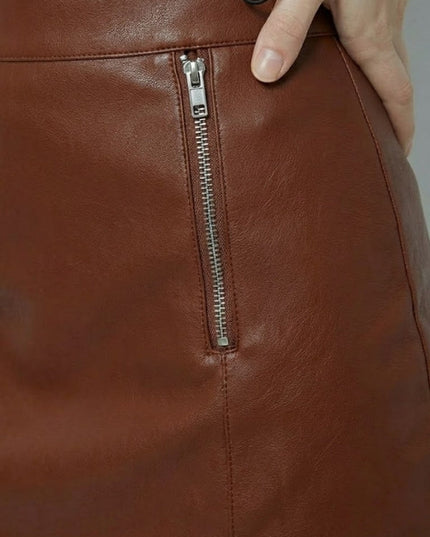 Close-up of a brown leather bag with a zipper, held by a hand.