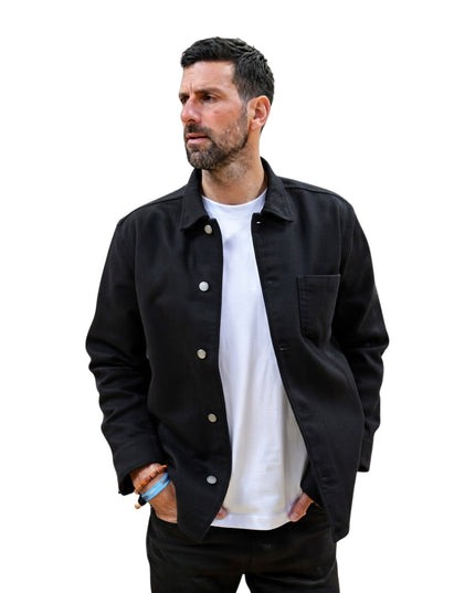 Man wearing a black jacket over a white shirt on a white background