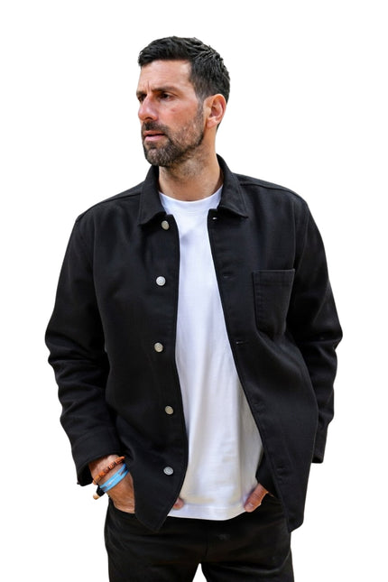 Man wearing a black jacket over a white shirt on a white background