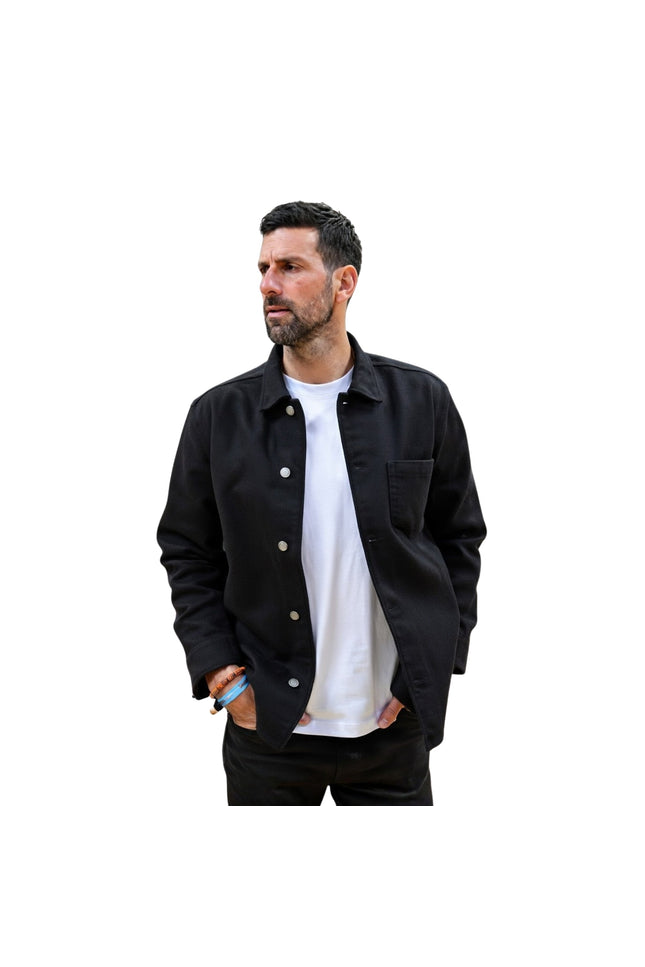 Man wearing a black jacket over a white shirt on a white background