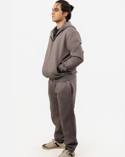Person wearing a gray tracksuit on a white background