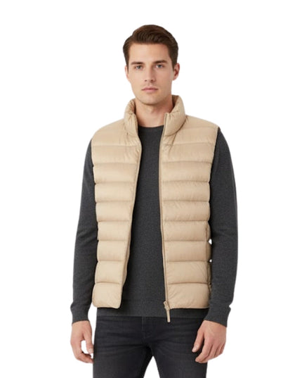 Man wearing a beige puffer vest over a dark long-sleeve shirt on a white background