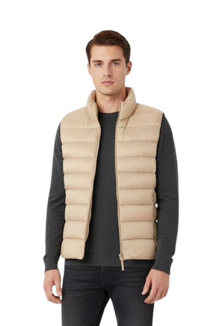Man wearing a beige puffer vest over a dark long-sleeve shirt on a white background