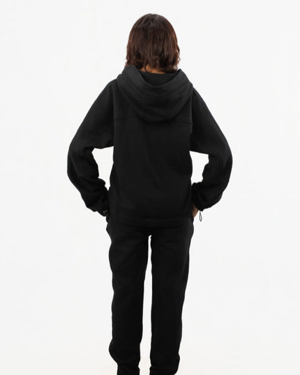 Person wearing a black hoodie and pants on a white background