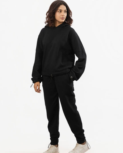 Person wearing a black hoodie and black pants on a white background