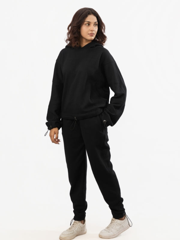 Person wearing a black hoodie and black pants on a white background