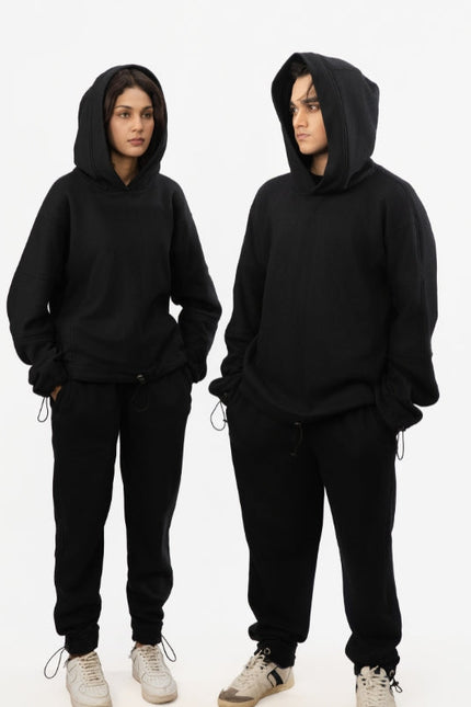 Two people wearing black hoodies and pants on a white background