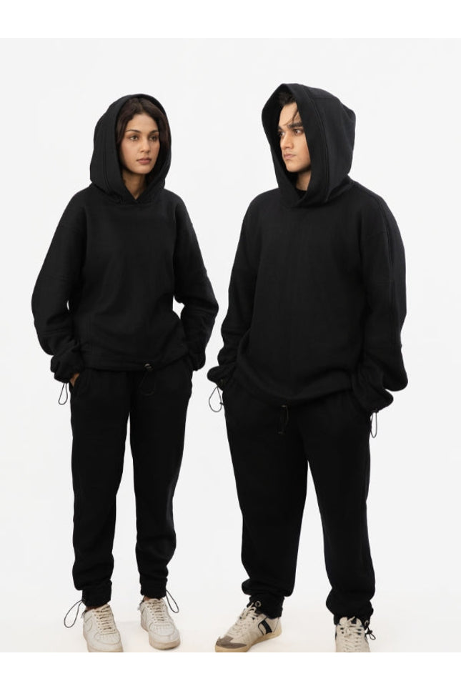 Two people wearing black hoodies and pants on a white background