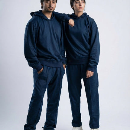 Two people wearing matching navy blue tracksuits on a white background