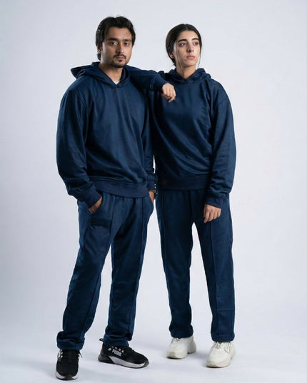 Two people wearing matching navy blue tracksuits on a white background