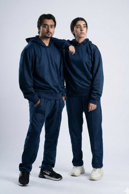 Two people wearing matching navy blue tracksuits on a white background