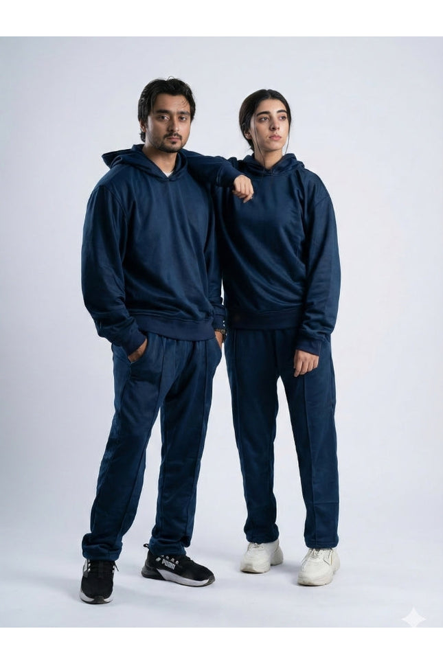 Two people wearing matching navy blue tracksuits on a white background