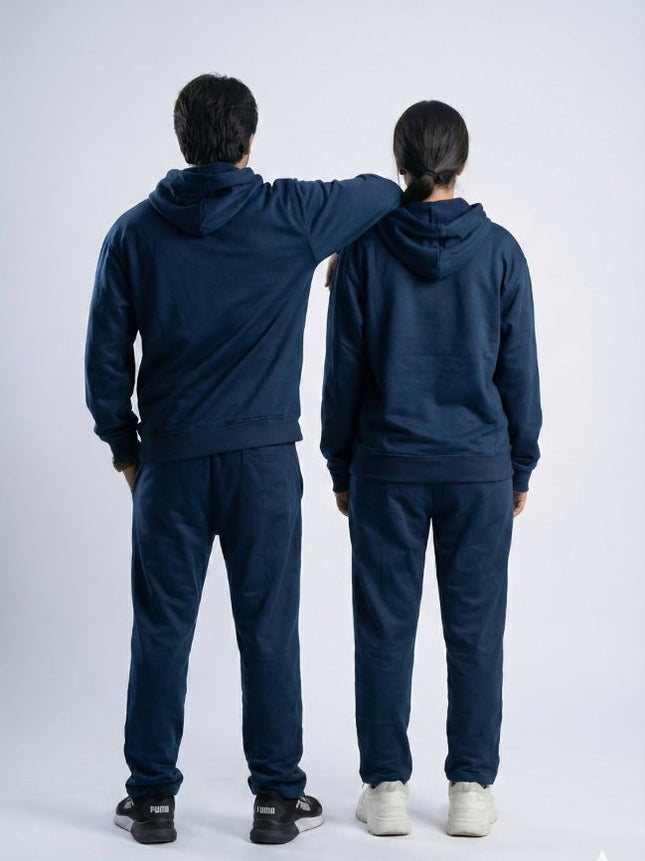 Two people wearing matching navy blue tracksuits standing back-to-back on a white background