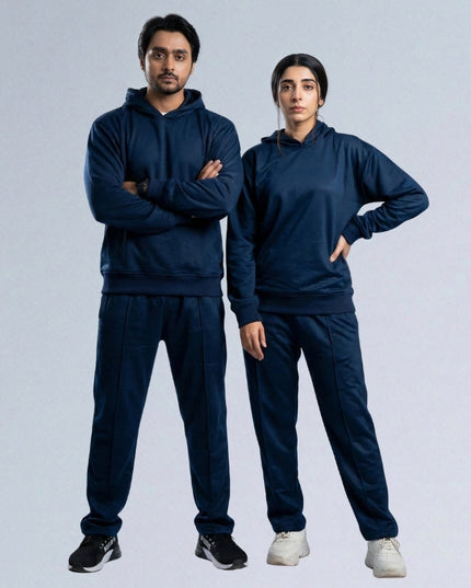 Two people wearing matching navy blue tracksuits on a light gray background