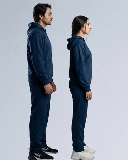 Two people wearing matching navy blue tracksuits standing side by side on a light gray background.