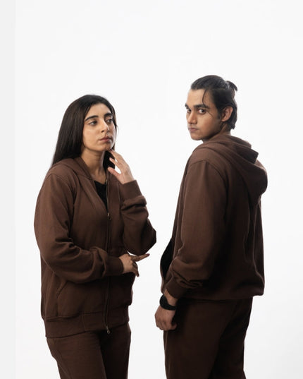 Two people wearing brown tracksuits on a white background