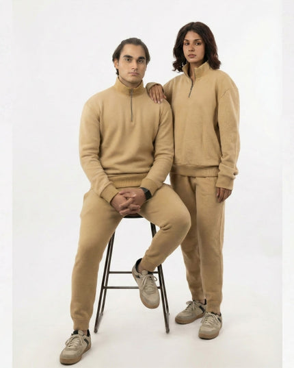 Two people wearing matching beige outfits on a white background