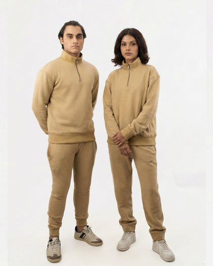 Two people wearing matching beige outfits on a white background