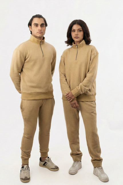Two people wearing matching beige outfits on a white background