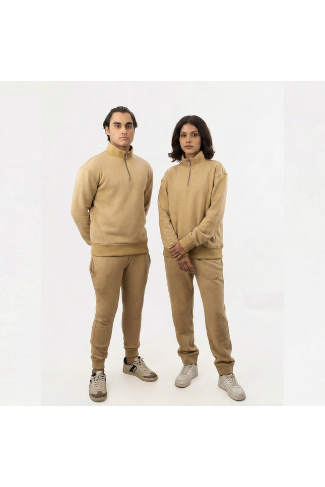 Two people wearing matching beige outfits on a white background