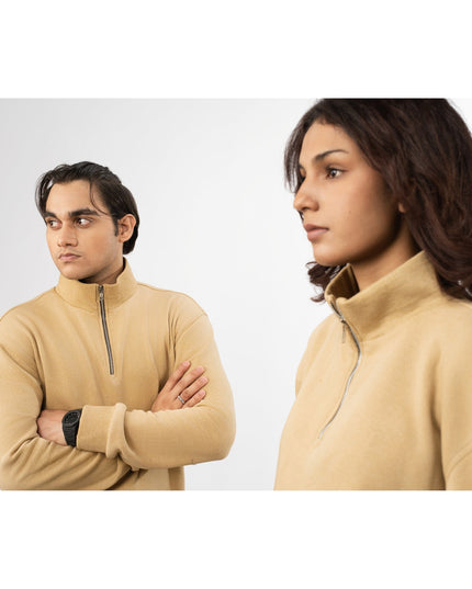Two people wearing beige half-zip sweatshirts against a white background