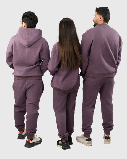 Three people wearing matching purple tracksuits from behind on a white background