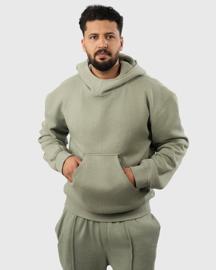 Man wearing a green hoodie and pants on a light gray background