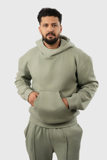 Man wearing a green hoodie and pants on a light gray background