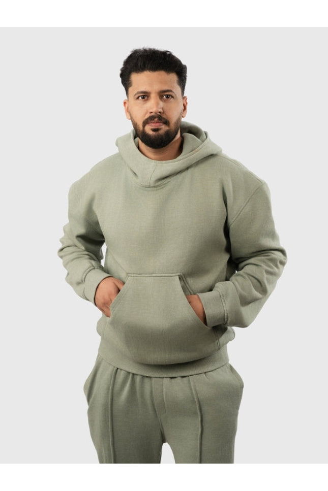 Man wearing a green hoodie and pants on a light gray background
