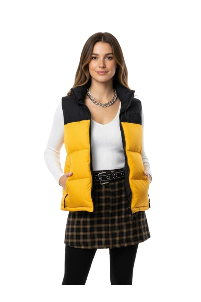 Woman wearing a yellow and black puffer vest on a white background