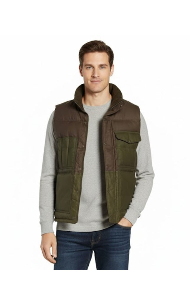 Man wearing a brown and green vest over a gray sweater on a white background