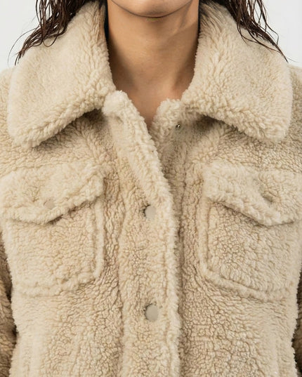 Close-up of a person wearing a beige sherpa jacket.