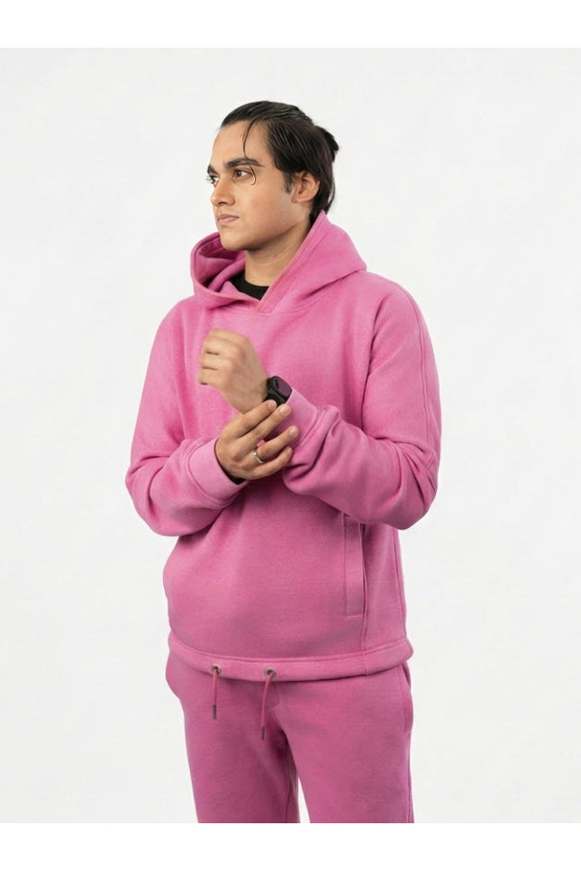 Person wearing a pink hoodie and pants on a white background
