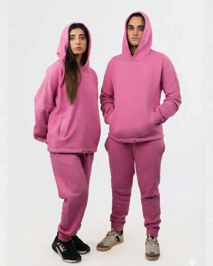 Two people wearing matching pink hoodie and sweatpants sets on a white background