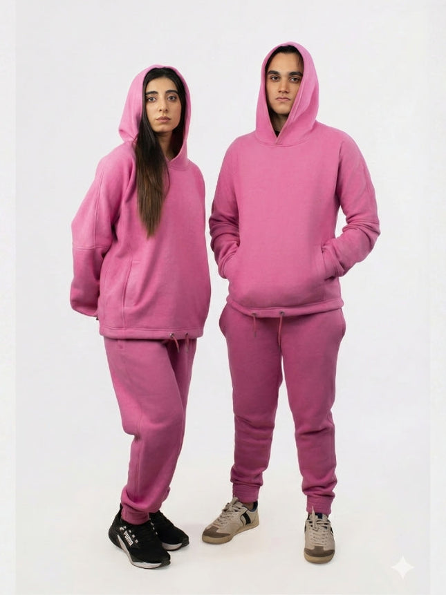Two people wearing matching pink hoodie and sweatpants sets on a white background