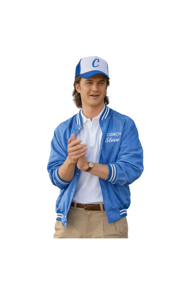 Man wearing a blue jacket with 'Coach Steve' text, white shirt, tan pants, and blue cap on a white background