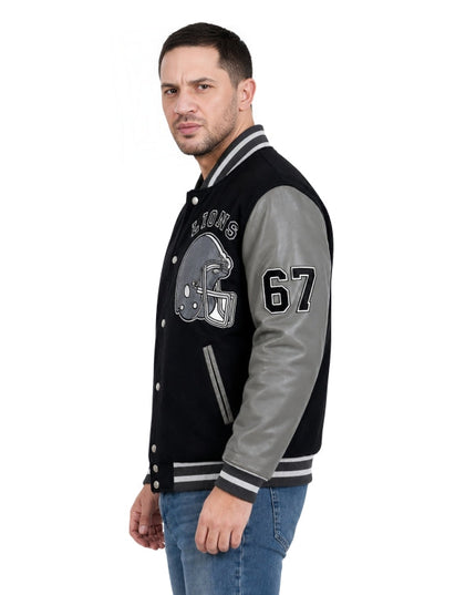 Man wearing a black and gray varsity jacket with letterman design on a white background