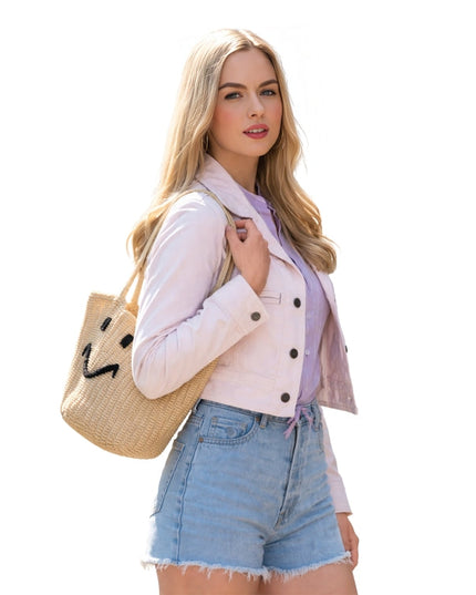 Woman holding a straw bag with a smiley face design on a white background