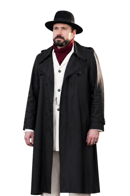 Man wearing a long black coat, hat, and red sweater on a white background
