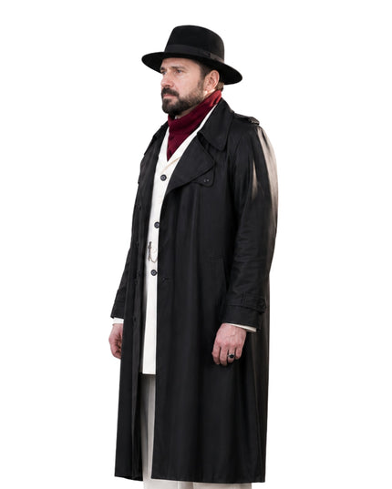 Man wearing a long black coat, white shirt, and black hat on a white background