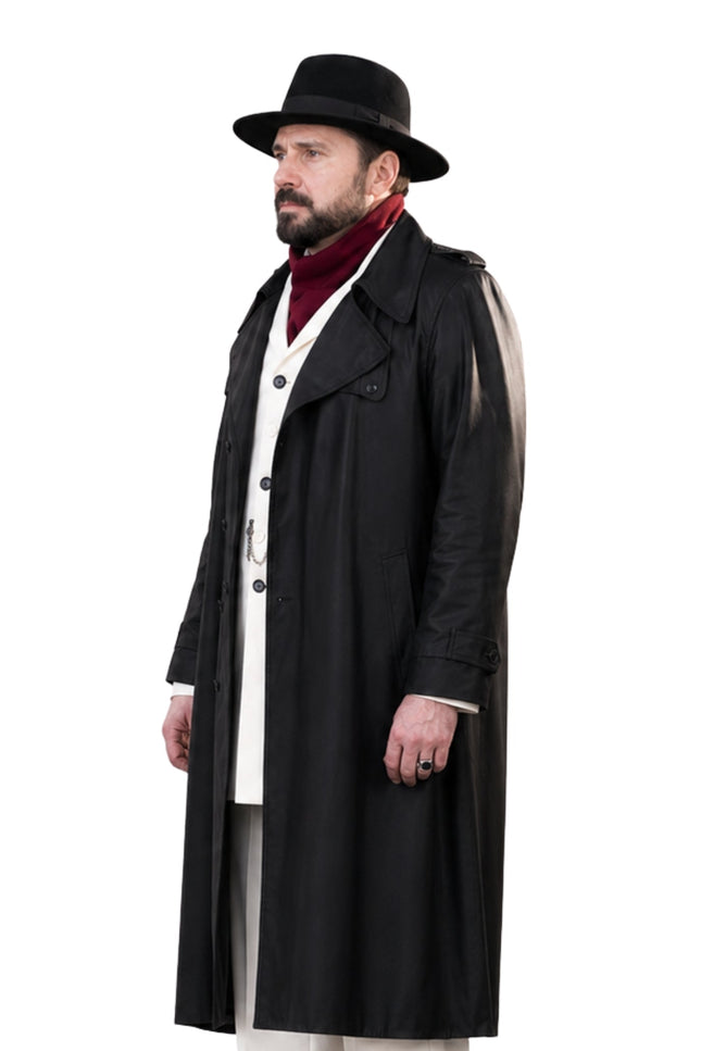 Man wearing a long black coat, white shirt, and black hat on a white background