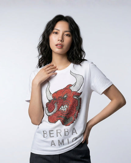 Woman wearing a white t-shirt with a red bull graphic and 'BERBA AMIC' text on a light gray background